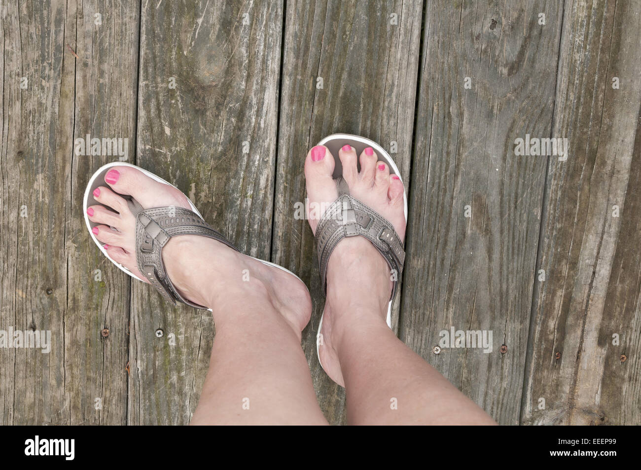 Pieds de femme debout sur une terrasse en bois dans une paire de sandales  couleur bronze ou tongs Photo Stock - Alamy
