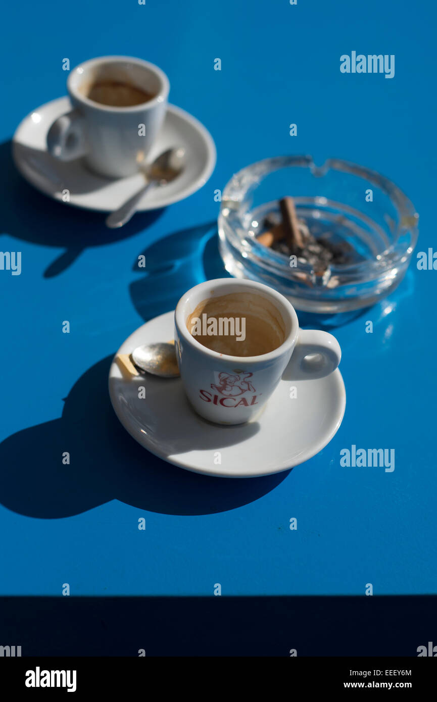 Deux tasses à café expresso vide et un cendrier sur un tableau bleu Banque D'Images Deux tasses à café expresso vide et un cendrier sur un tableau bleu Banque D'Images