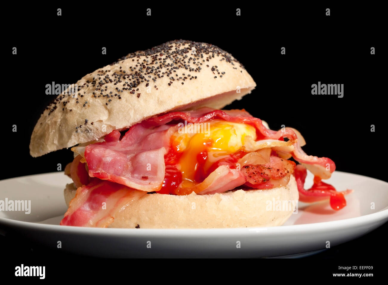 Une photographie du gros plan d'un Bacon et egg roll à la sauce tomate avec un fond noir. Banque D'Images