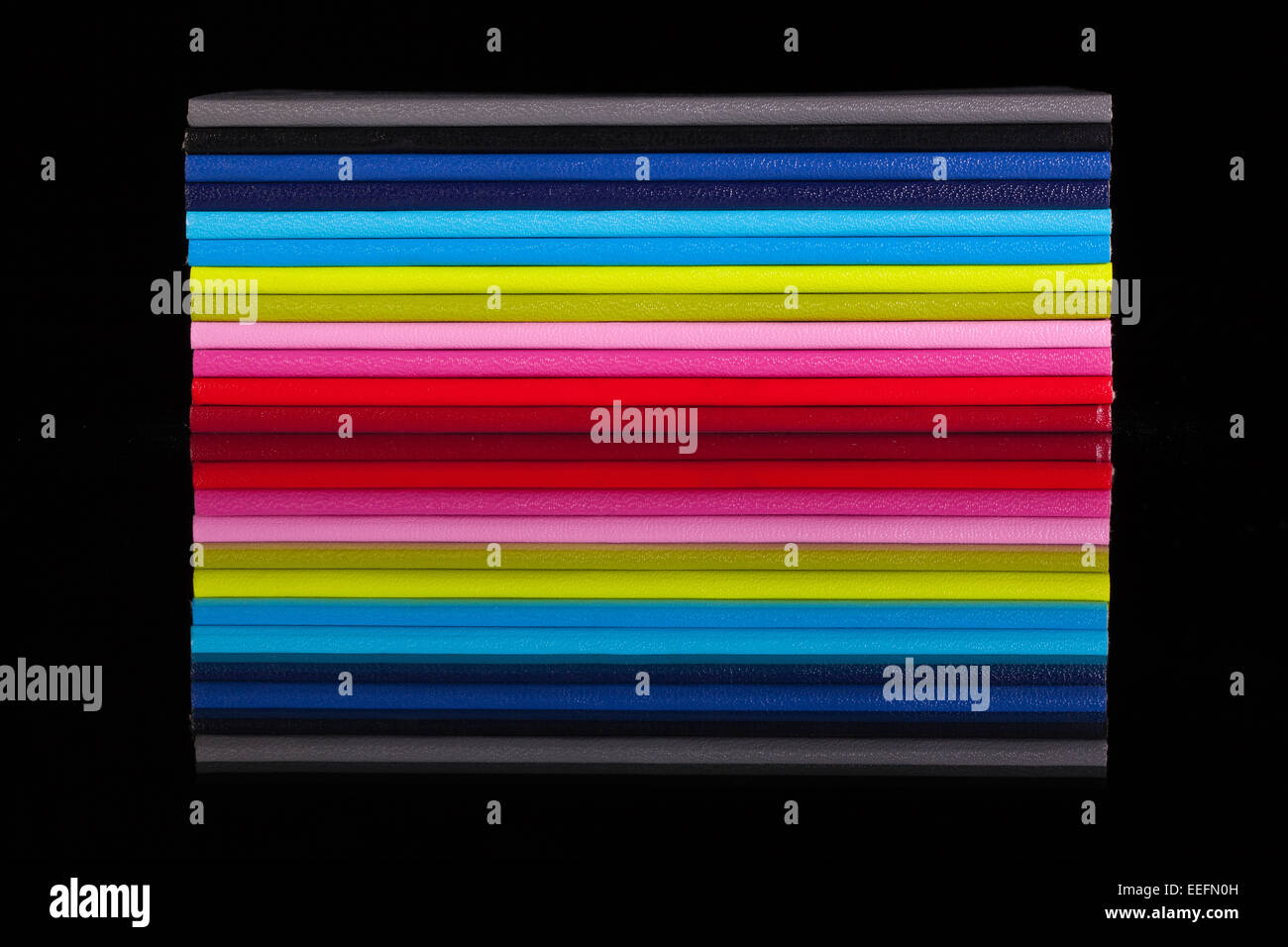 Douze journaux de couleur différente sur un bureau en verre noir Banque D'Images