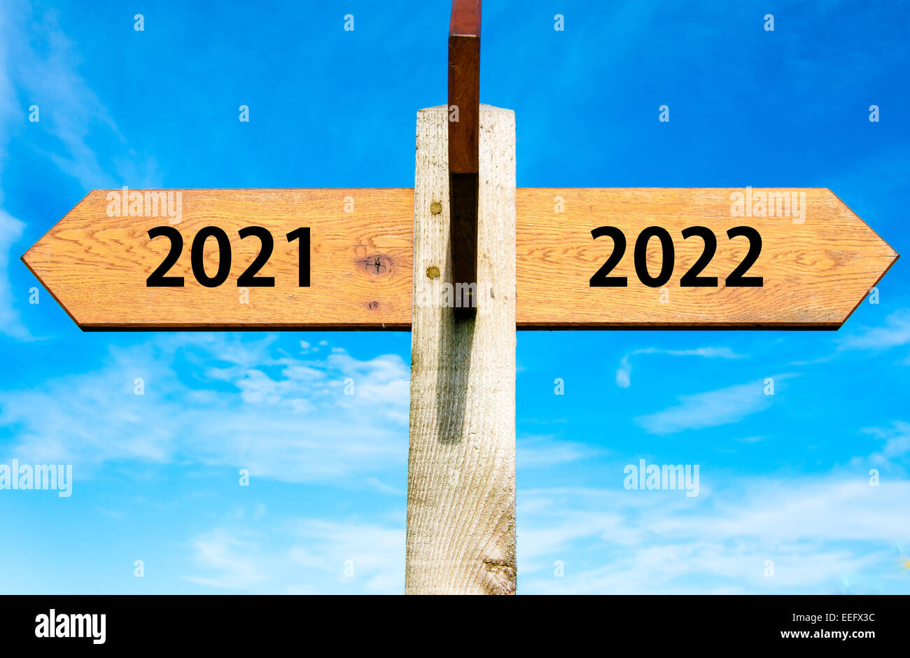 Panneau en bois avec deux flèches opposées sur ciel bleu clair, l'année 2021 et 2022 signes, bonne année conceptual image Banque D'Images