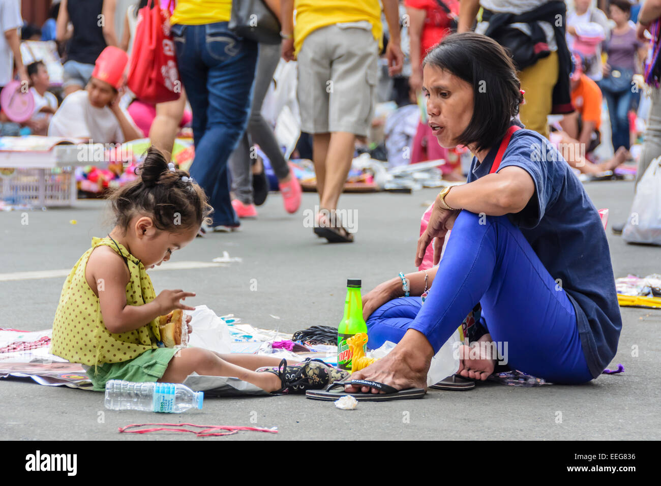 Intramuros, Manille, Philippines, 16 janvier 2015. Vendeur femme rss sa fille tout en faisant une pause la vente de souvenirs du pape dans une rue près de la cathédrale de Manille, Intramuros le vendredi 16 janvier 2015, où le Saint Père a été programmé pour célébrer la Sainte Messe avec les évêques, prêtres, religieux et d'autres au cours de sa visite apostolique aux Philippines. Banque D'Images