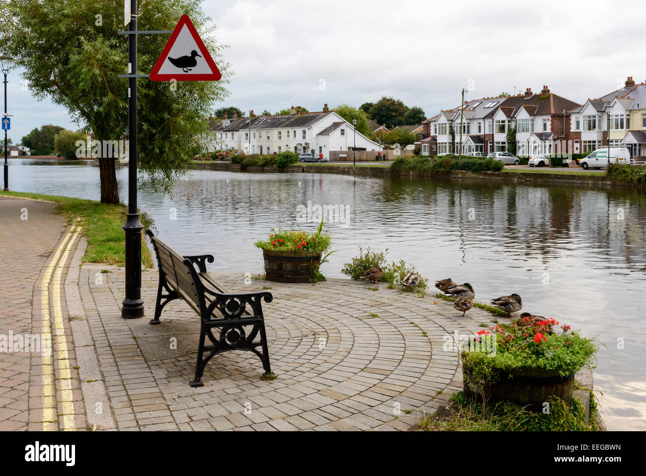 Vue de la mer village touristique montrant un signal d'avertissement pour les canards près d'un banc sur le quai de l'étang de la mer à proximité Banque D'Images