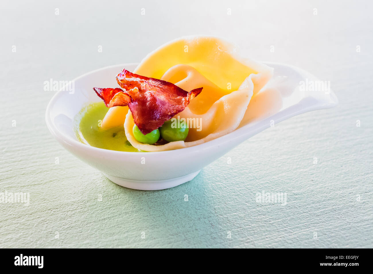 Les pâtes maison vrac remplis de fromage mascarpone et le Parmesan, le zeste de citron servi avec des petits pois, purée de petits pois et chiips Banque D'Images