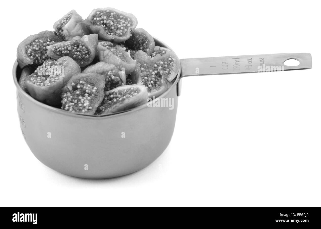 Figues hachées dans une tasse mesurer, isolé sur fond blanc - traitement monochrome Banque D'Images