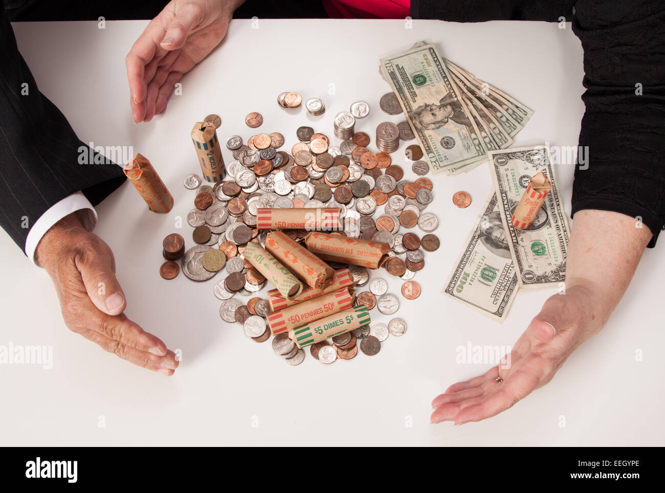 US Coins. Les projets de loi, et Coin Rolls avec mains et bras regroupant l'argent Banque D'Images