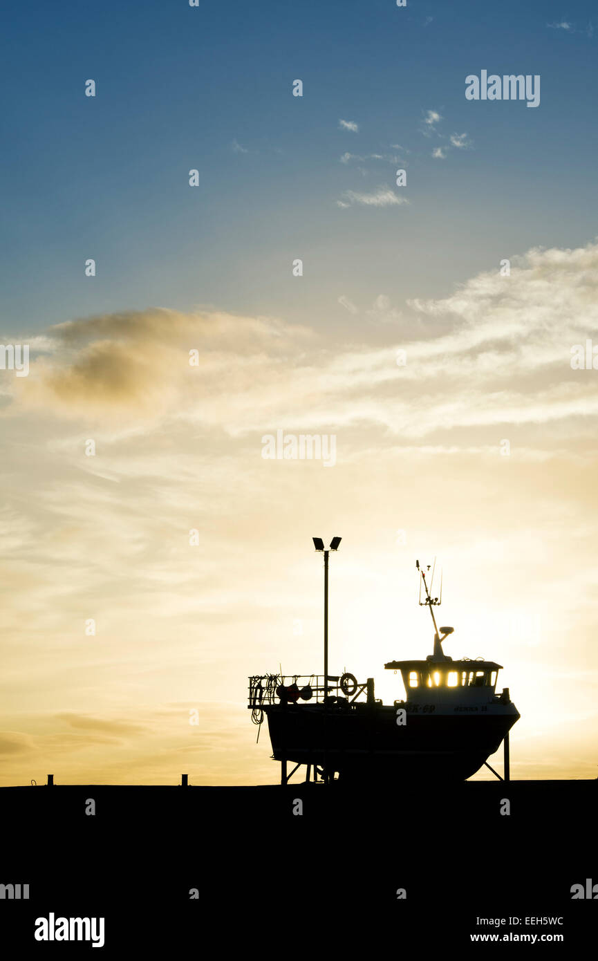 Bateau de pêche sur la terre ferme au lever du soleil dans le port de Lindisfarne, Holy Island, Northumberland, Angleterre. Silhouette Banque D'Images