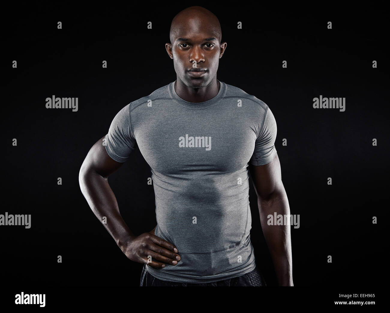 Portrait of muscular young man in sportswear looking at camera sur fond noir. Les pays africains qui pose l'athlète confiant Banque D'Images