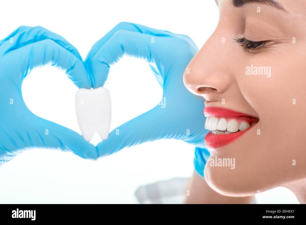 Fermer portrait de jeune femme dentiste avec large sourire sain holding dent artificielle sur fond blanc Banque D'Images