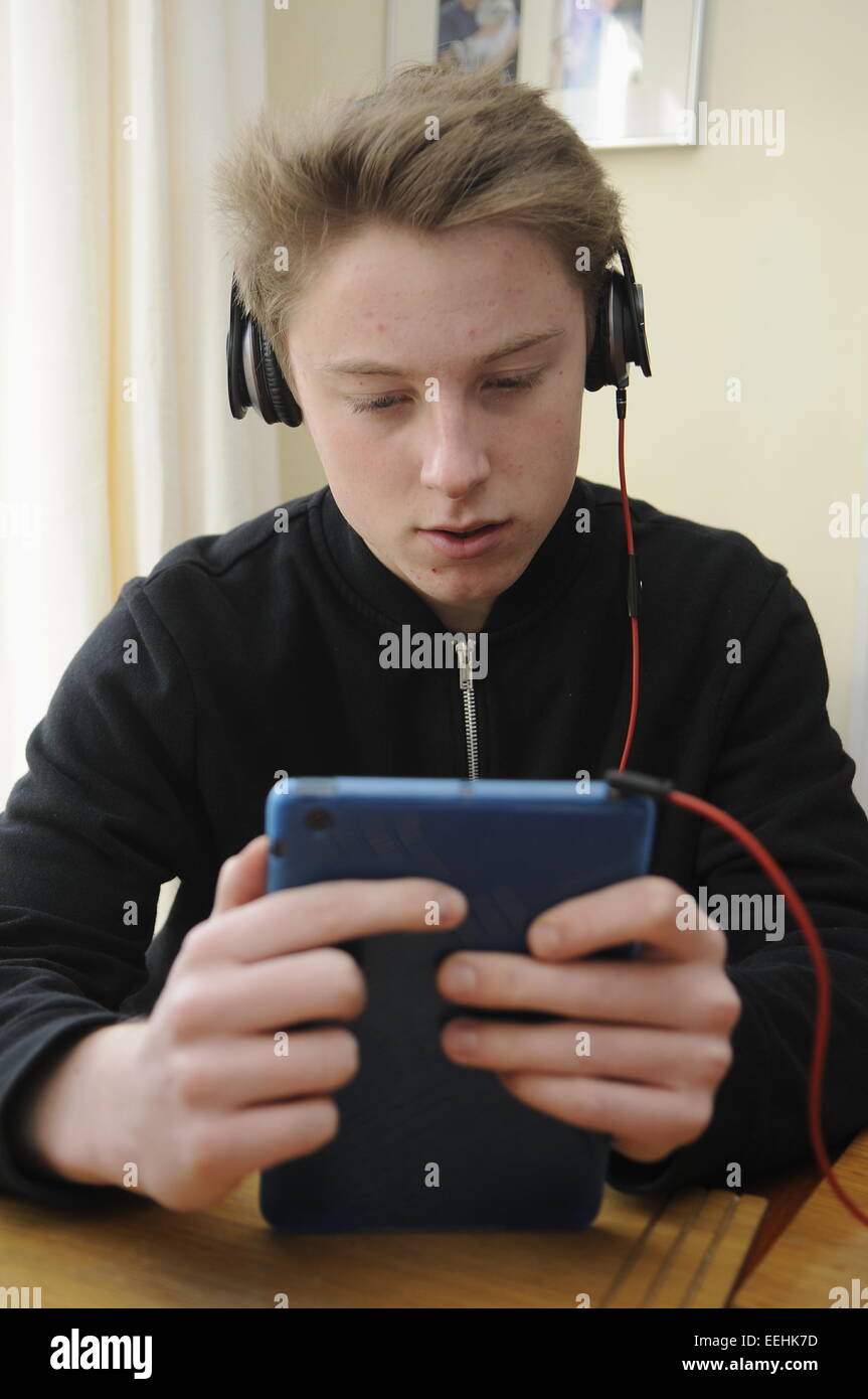 Teenage Boy en utilisant un Apple iPad Mini et écouteurs Beats Banque D'Images