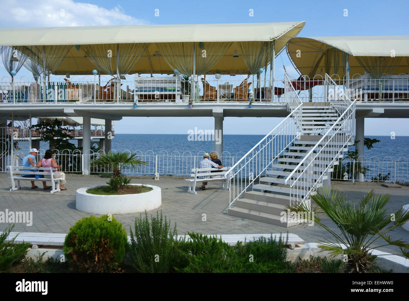 Des couples coin sur les bancs près du restaurant en bord de mer dans la station balnéaire d'Alouchta, Crimée, Russie Banque D'Images