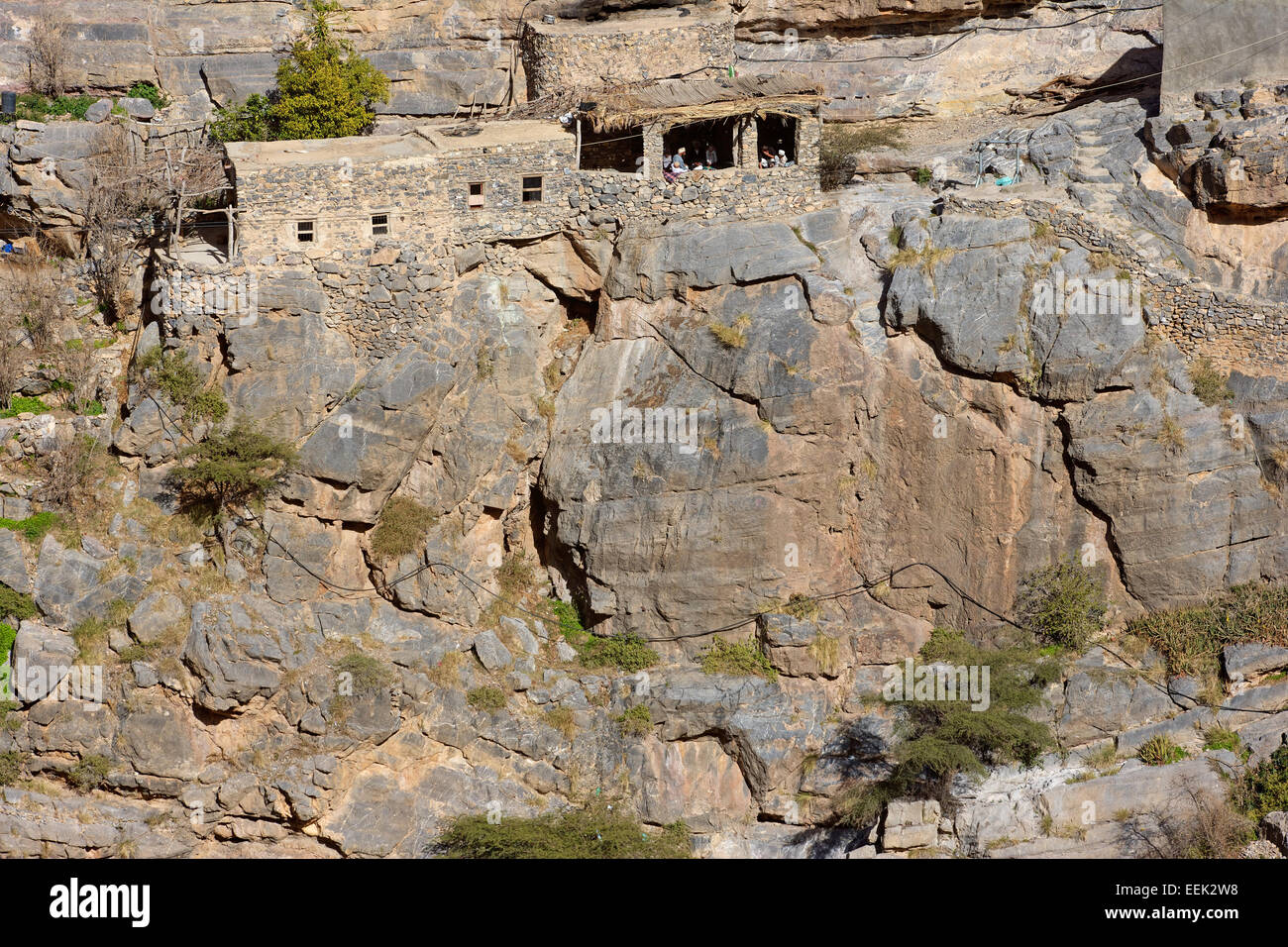 Les hommes omanais dans leur majlis, ou d'un lieu de rencontre, au milieu des maisons traditionnelles en pierre dans un petit hameau de falaise dans le Djebel Akhdar, Oman. Banque D'Images