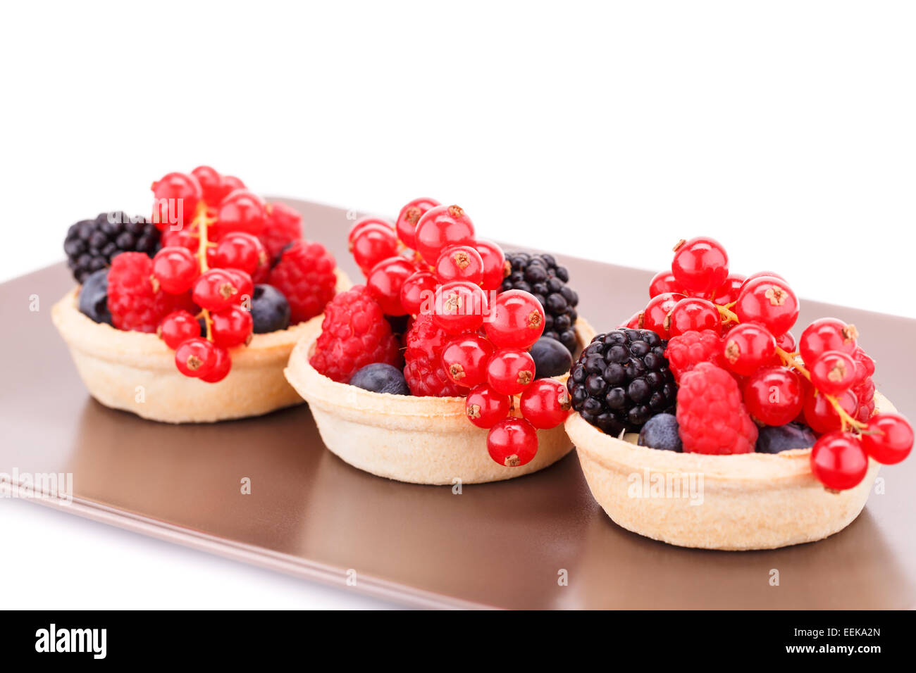 Tartelettes aux fruits frais mûrs dans sur la plaque brune. Banque D'Images