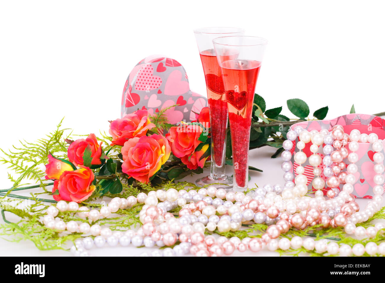 Deux verres, fleurs, colliers de perles colorées et boîte-cadeau sur fond blanc. Banque D'Images
