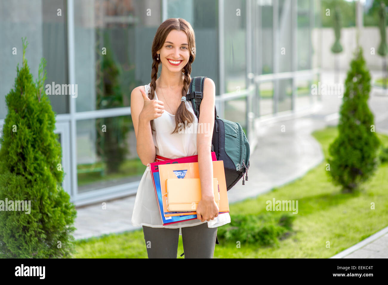 Jeune fille étudiante à l'extérieur avec sac à dos et des livres à l'école et souriant Banque D'Images