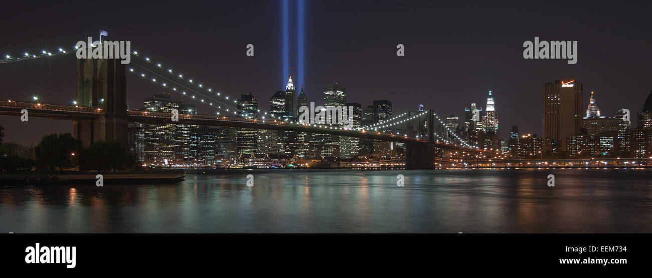 USA, New York, New York City skyline illuminé, avec pont de Brooklyn les rayons de lumière bleue Banque D'Images