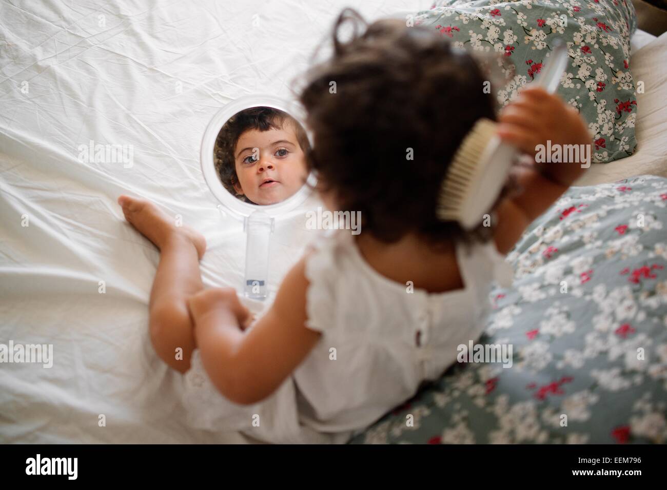 Girl (2-3) peigner les cheveux sur le lit avec miroir Banque D'Images