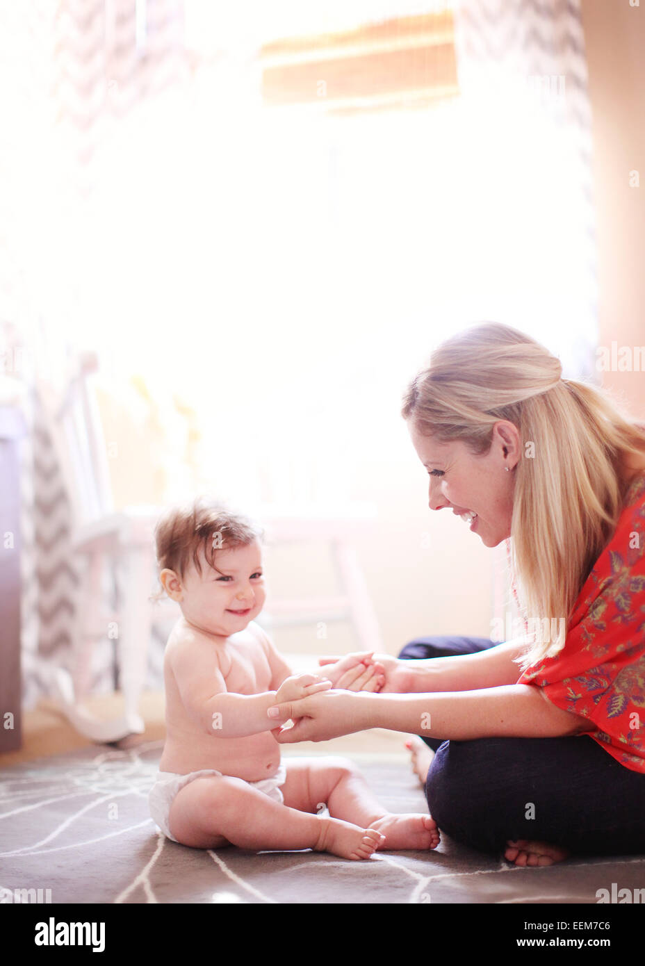 Baby Girl sitting on floor avec la mère à la maison Banque D'Images
