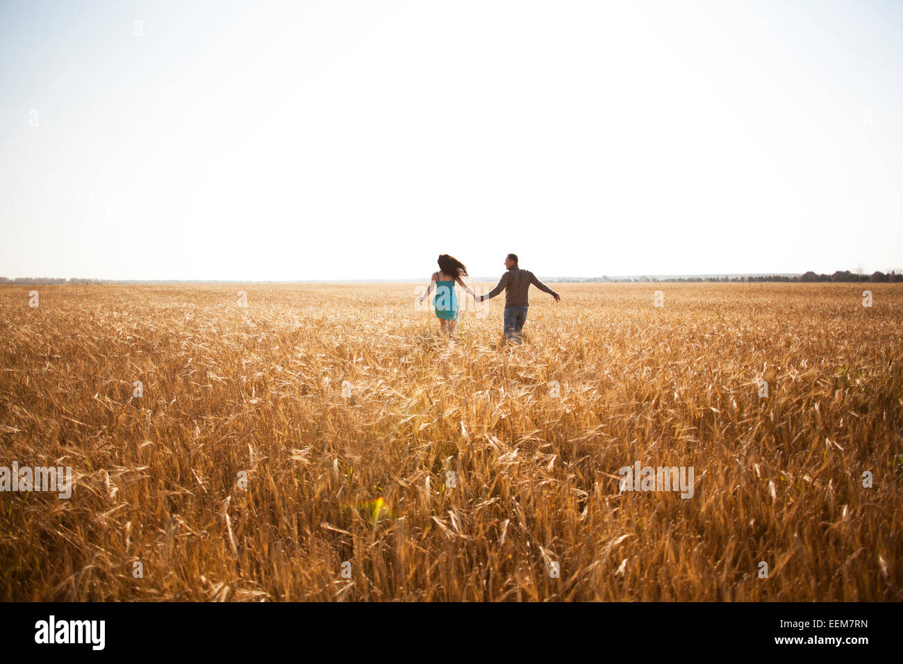 Caucasian couple running in rural field Banque D'Images
