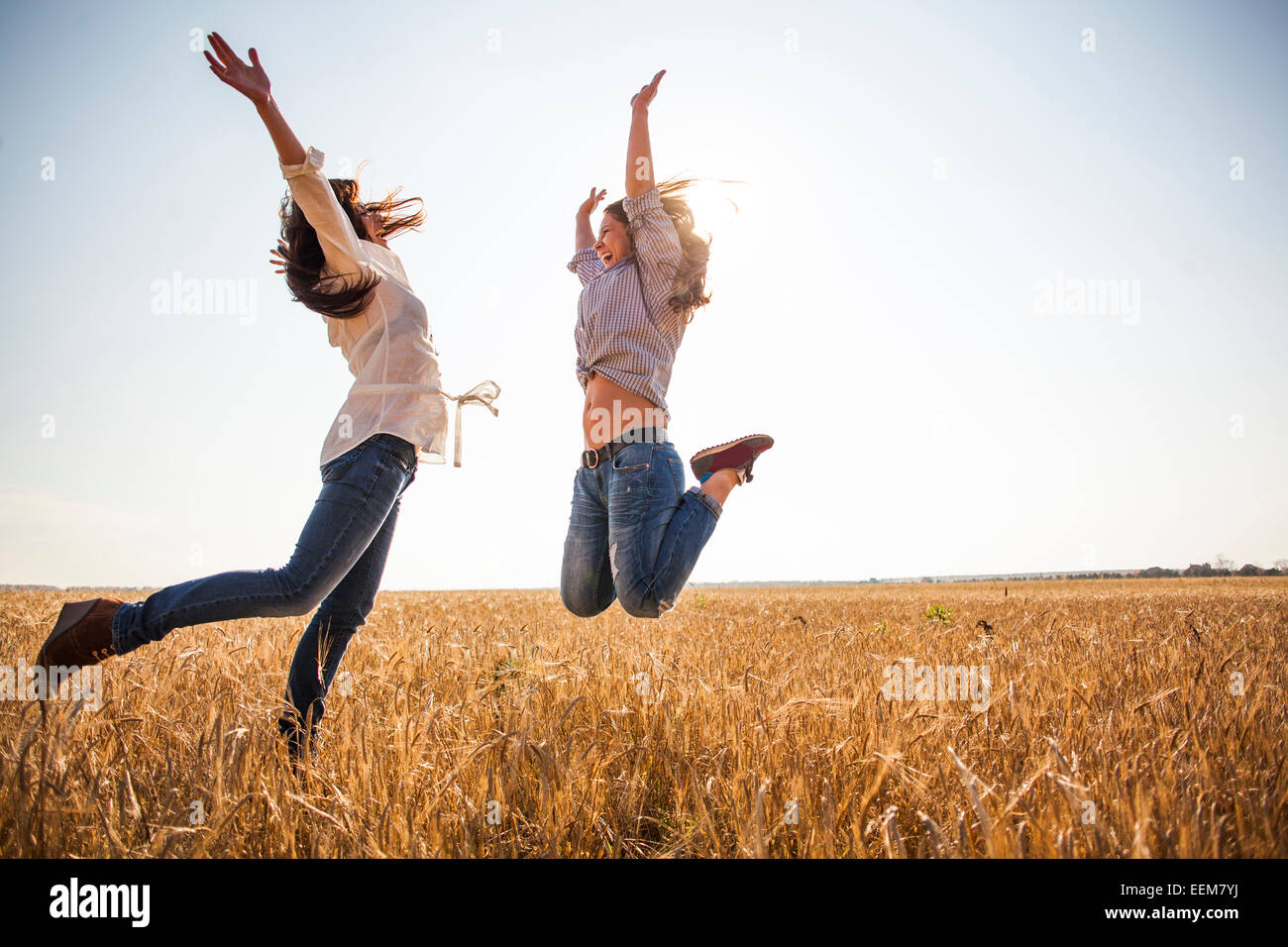 Les femmes de race blanche sauter de joie in rural field Banque D'Images