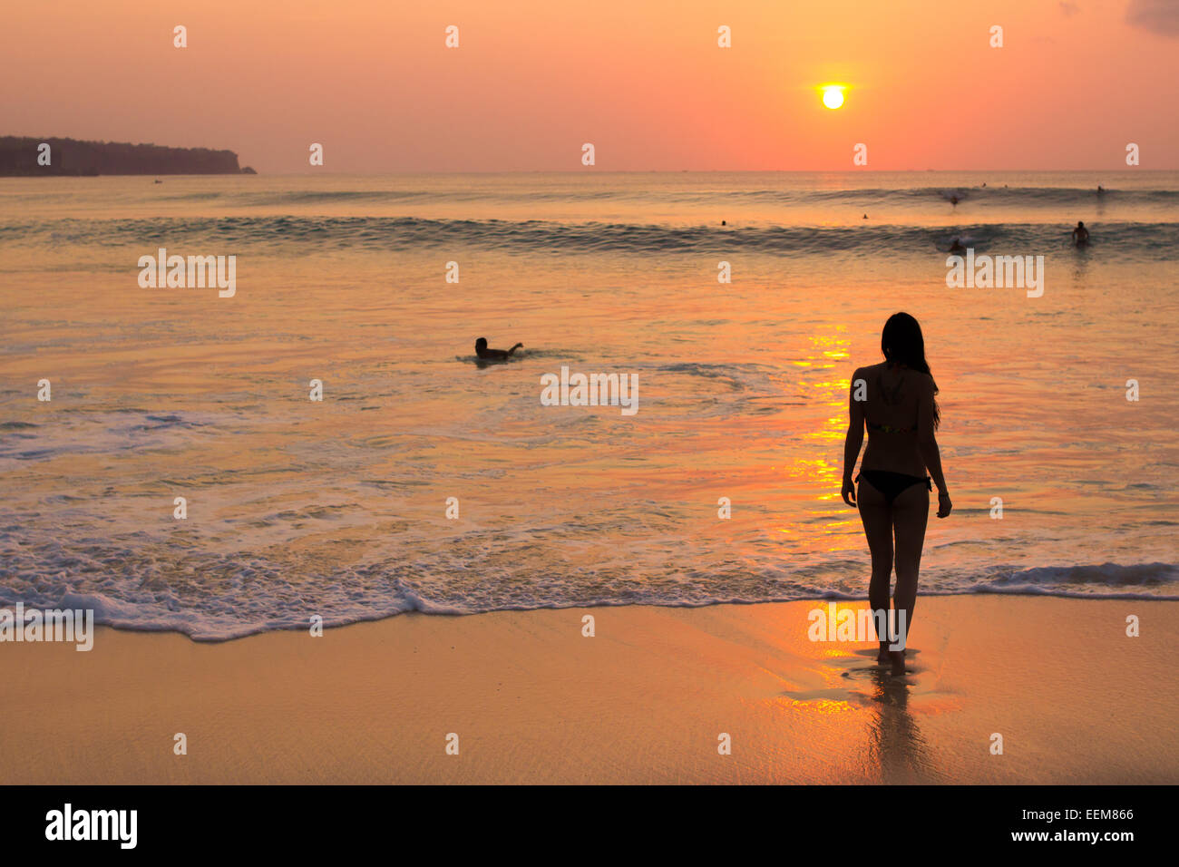 L'INDONÉSIE, Bali, Femme regardant le coucher du soleil sur la plage Banque D'Images