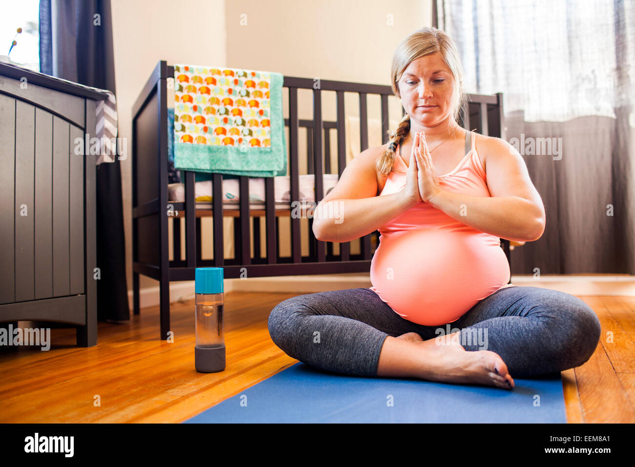 Pregnant Caucasian woman meditating in nursery Banque D'Images