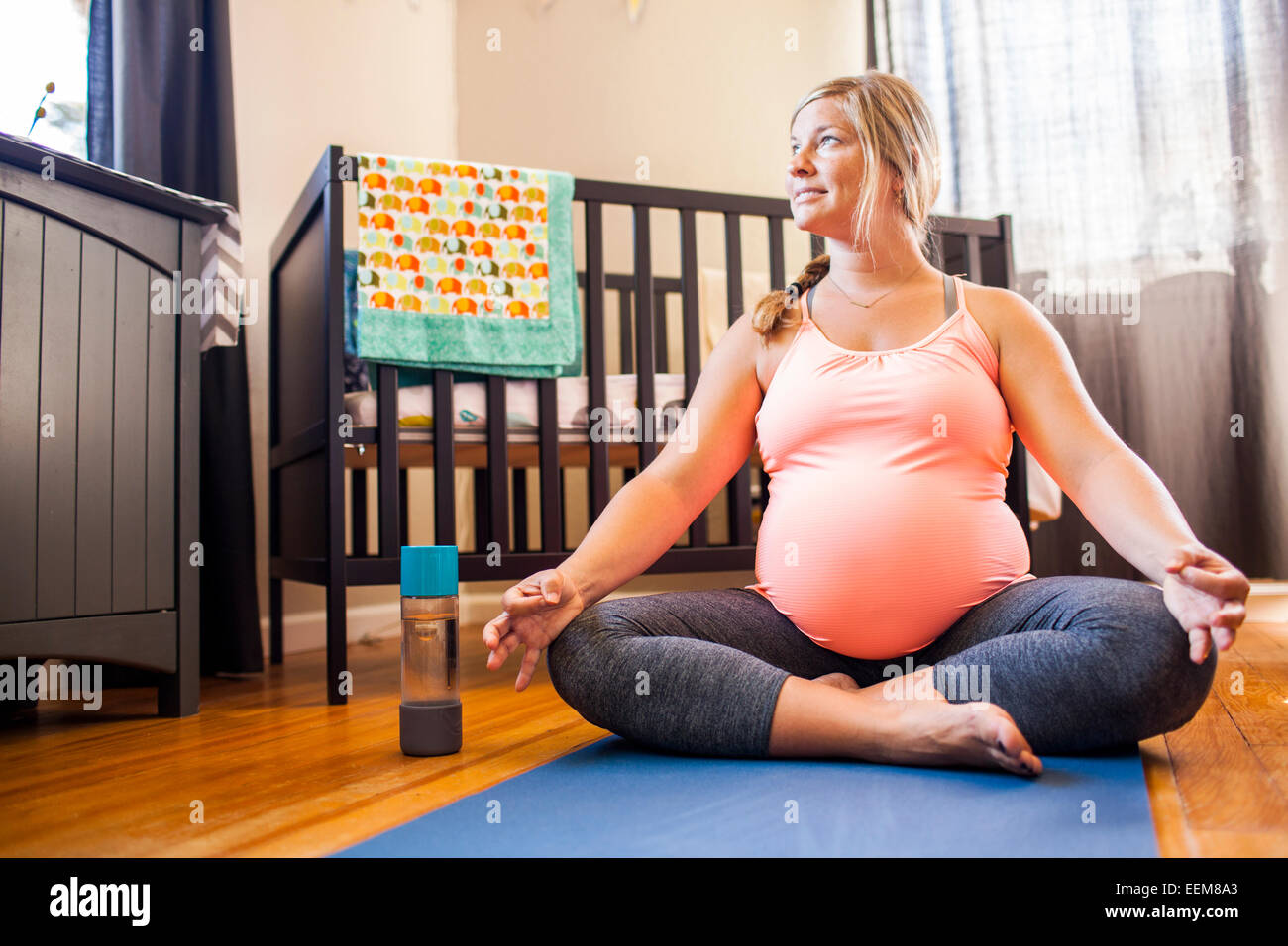 Pregnant Caucasian woman meditating in nursery Banque D'Images