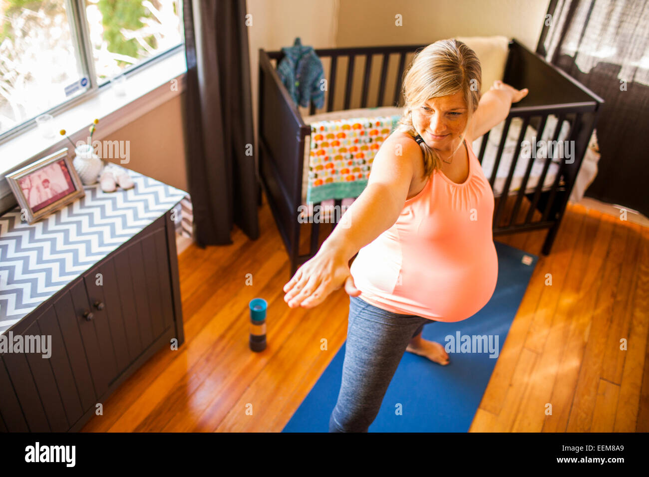 Pregnant Caucasian woman practicing yoga in nursery Banque D'Images