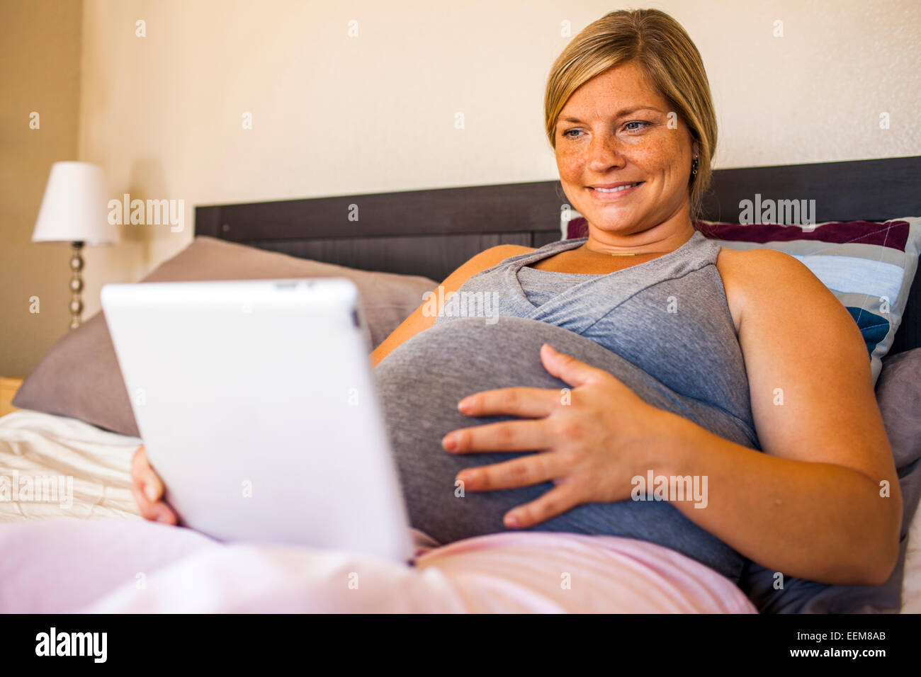 Femmes enceintes Caucasian woman using digital tablet in bed Banque D'Images