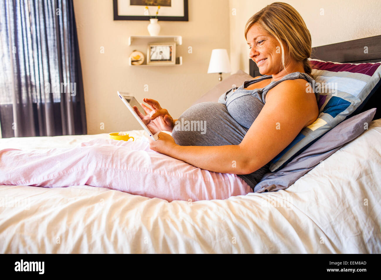 Femmes enceintes Caucasian woman using digital tablet in bed Banque D'Images
