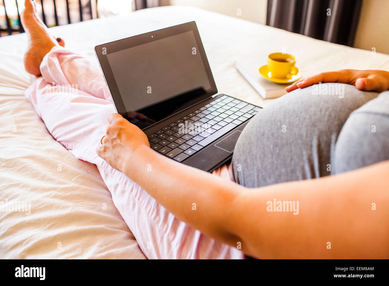 Pregnant Caucasian woman using laptop in bed Banque D'Images
