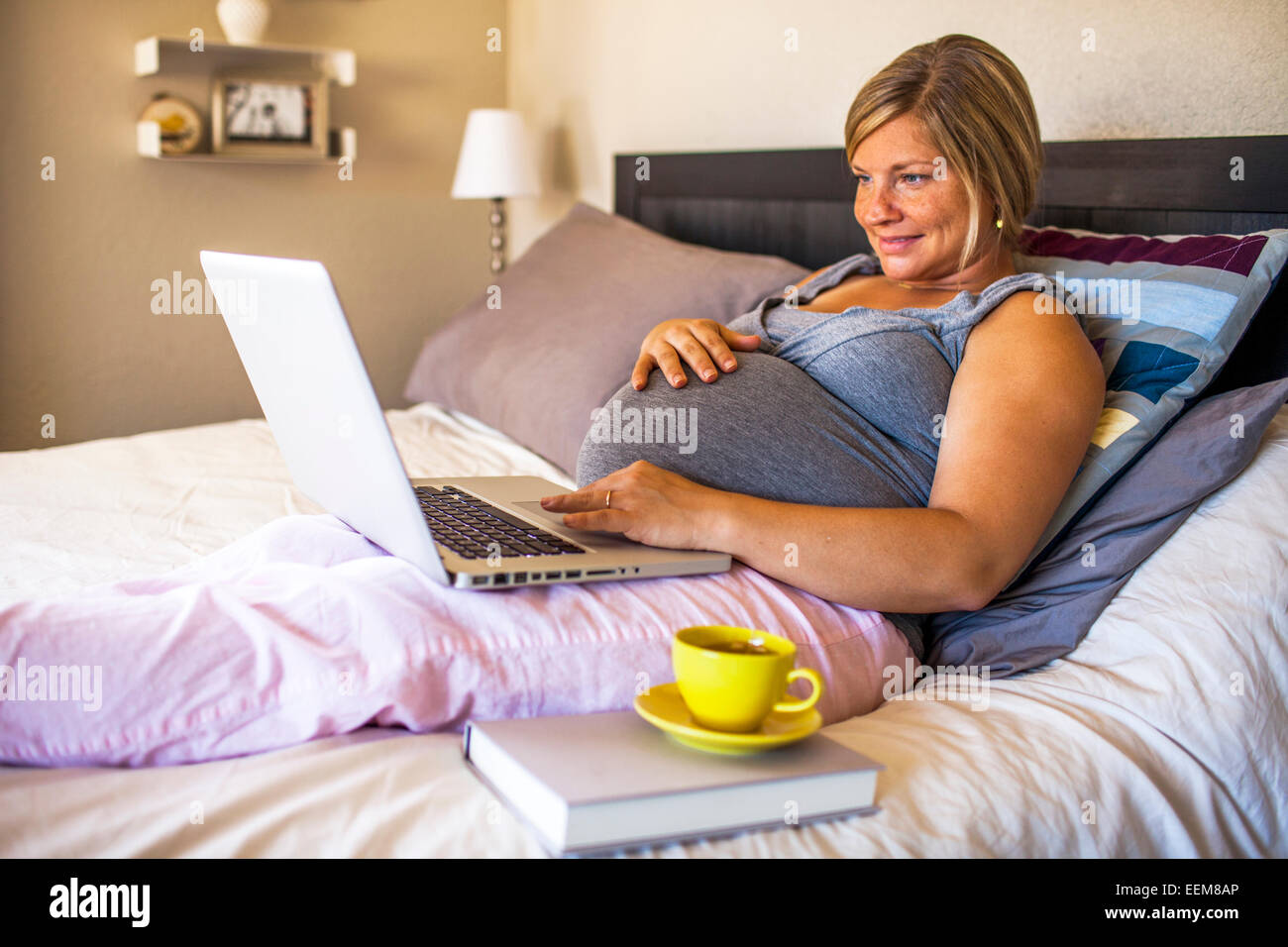 Pregnant Caucasian woman using laptop in bed Banque D'Images