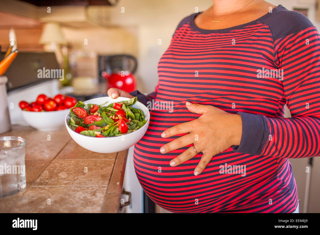 Femmes enceintes Caucasian mother holding salad in kitchen Banque D'Images