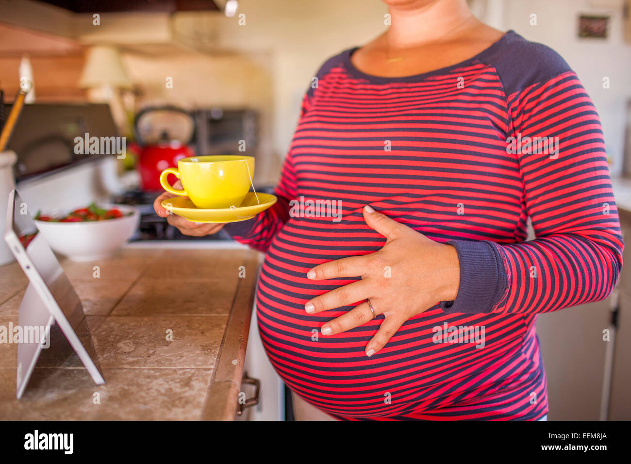 Femmes enceintes Caucasian mother holding tasse de thé dans la cuisine Banque D'Images