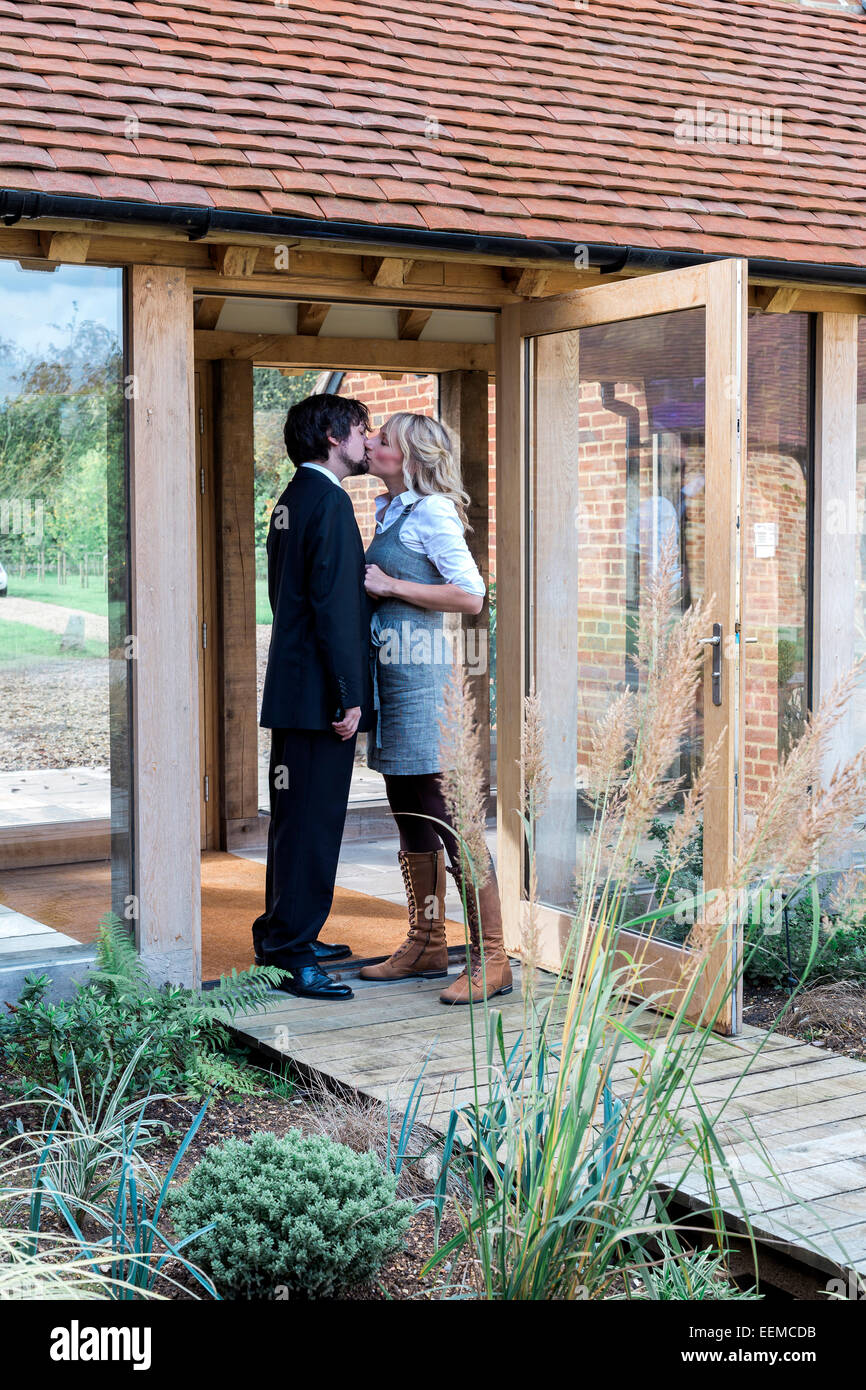Caucasian couple kissing at front door Banque D'Images