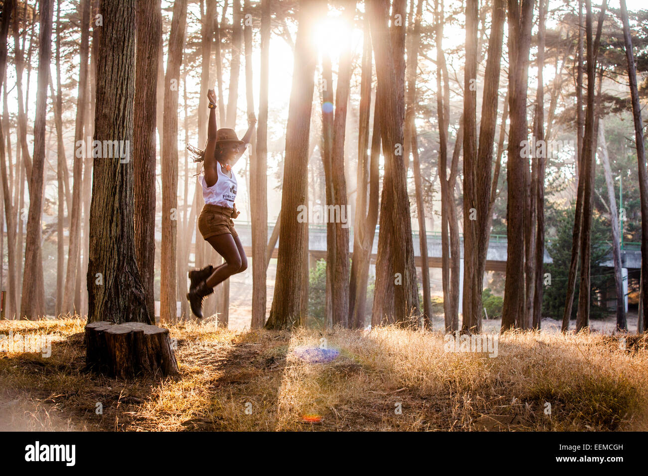 Black woman jumping de la souche dans la forêt ensoleillée Banque D'Images