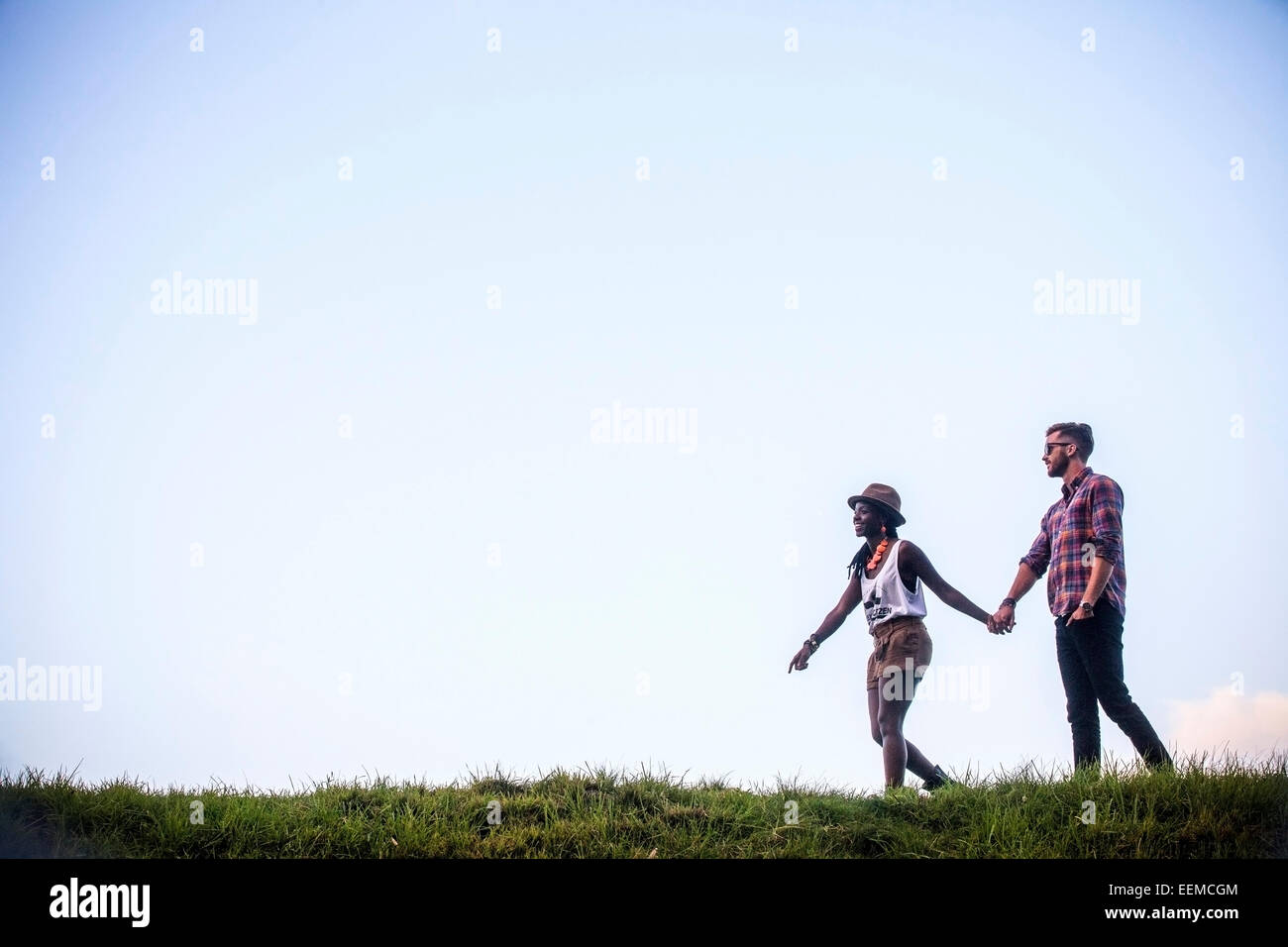 Couple walking together in grassy field Banque D'Images