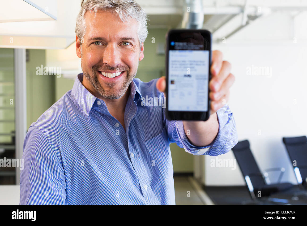 Caucasian businessman holding cell phone in office Banque D'Images