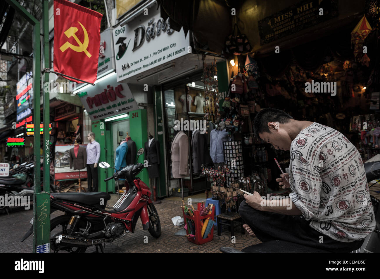 Un jeune homme est assis sur l'un des rues décorées de drapeaux avec le symbole communiste. Banque D'Images