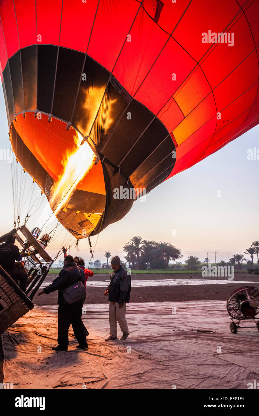 Gonfler un ballon à air chaud sur la rive ouest du Nil en Égypte au lever du soleil. Banque D'Images