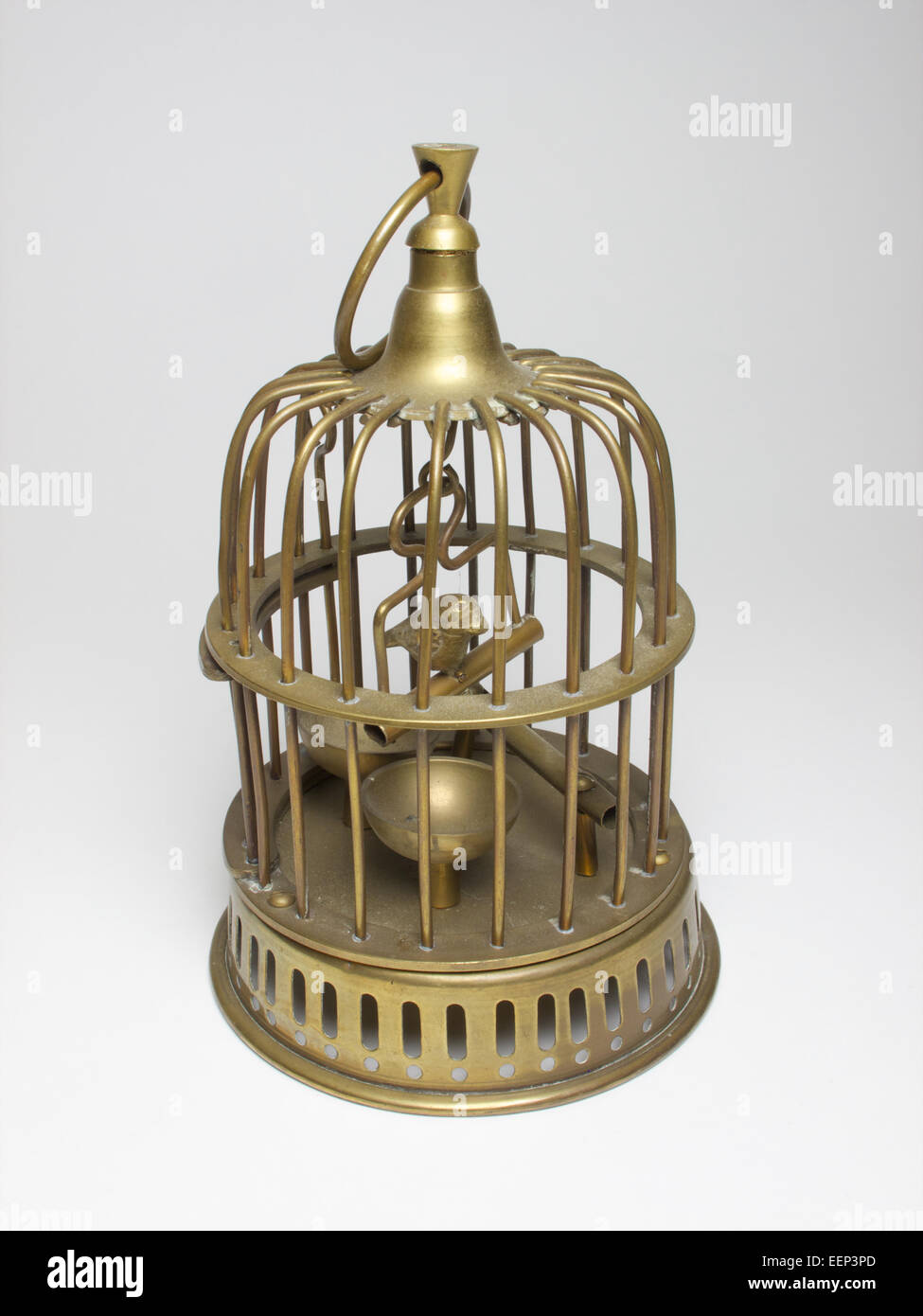 Cage à oiseaux en laiton miniature vintage avec ouverture latérale et une avec un oiseau posé sur une balançoire. La cage mesure environ 17,5cm Banque D'Images