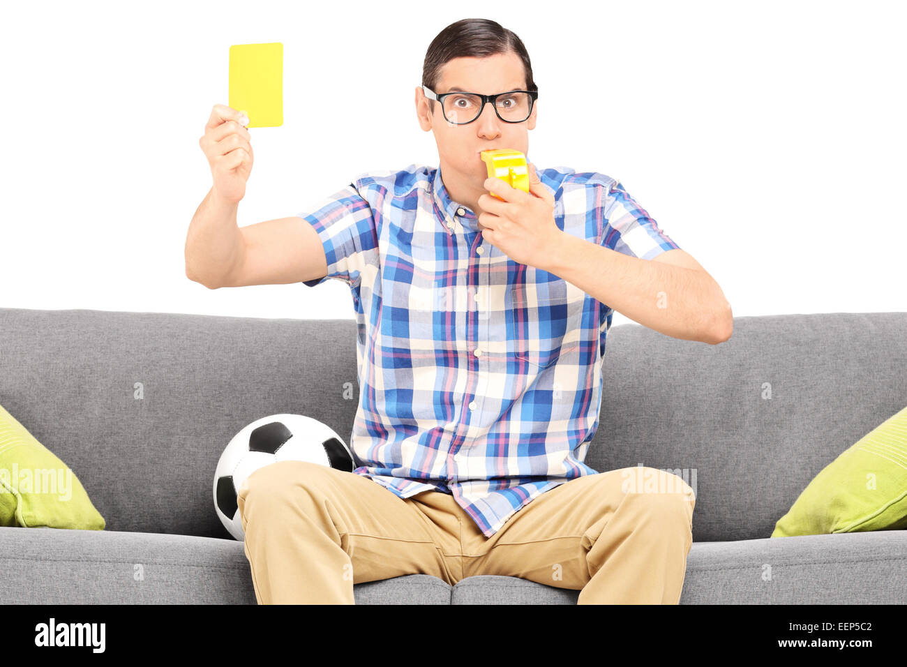Football fan en colère tenant une carte jaune assis sur table isolés contre fond blanc Banque D'Images