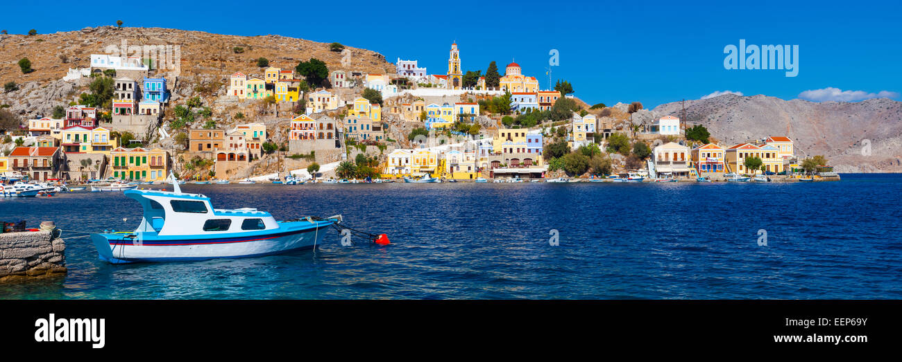 Vue panoramique tourné du port de Symi Grèce avec un bateau de pêche traditionnel au premier plan. La Grèce l'Europe. Banque D'Images