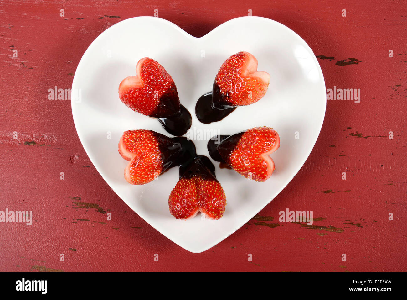 Happy Valentines Day fraises en forme de coeur au chocolat en forme de coeur sur plaque blanche sur fond de bois vintage rouge, overh Banque D'Images