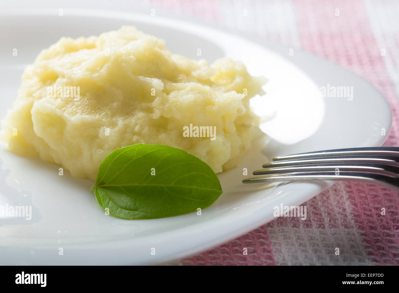 Purée de pommes de terre et basilic sur plaque blanche avec une fourchette Banque D'Images
