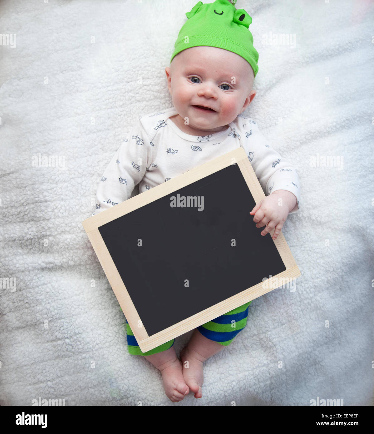 Smiling blue eyed baby boy holding a chalkboard Banque D'Images