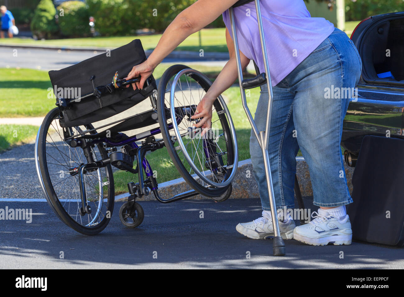 Femme avec Spina Bifida à l'aide de béquilles pour prendre à part pour fauteuil roulant dans la voiture Banque D'Images