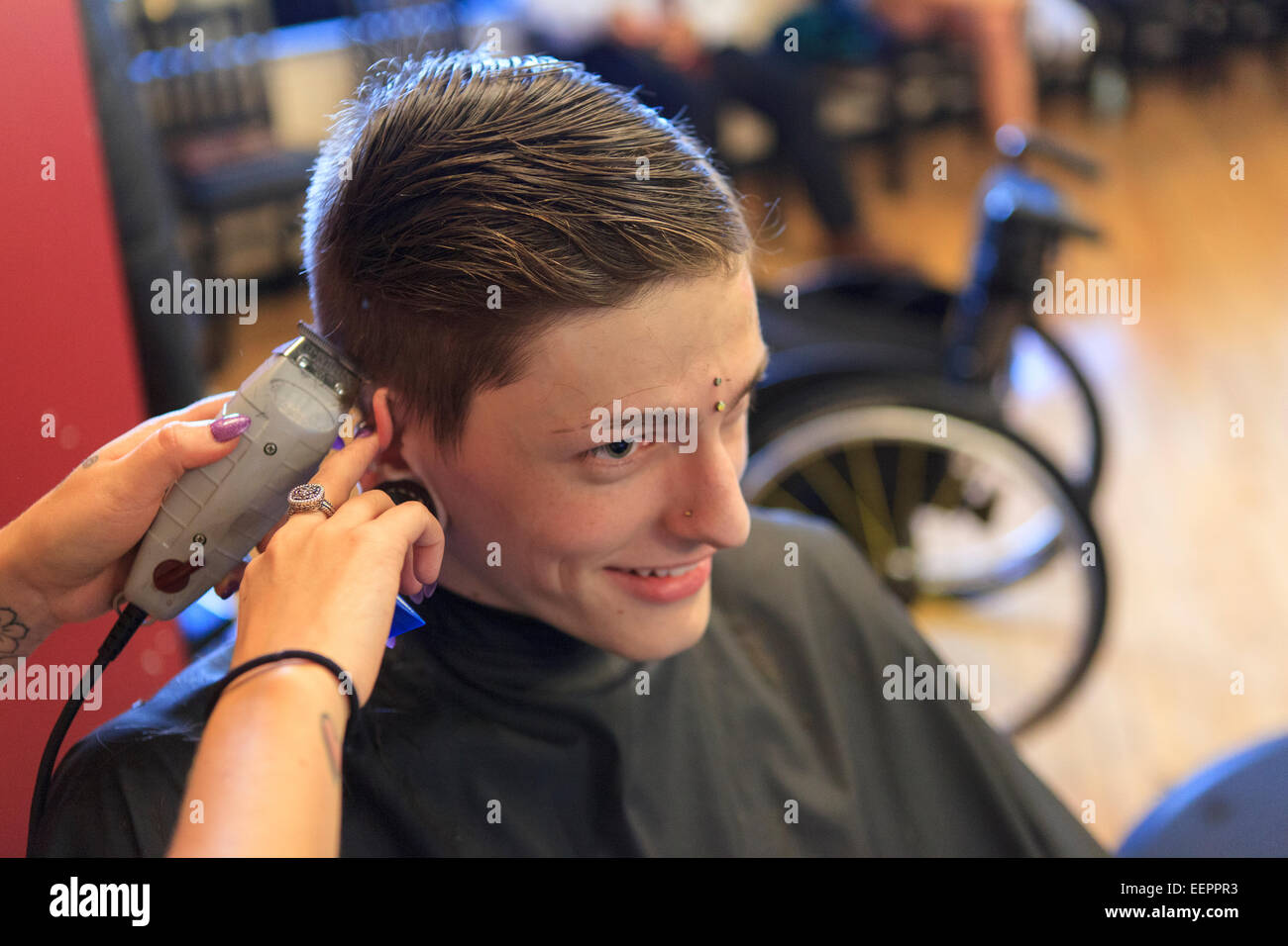 L'homme à la mode avec une lésion de la moelle épinière à un salon de coiffure pour une coupe de cheveux Banque D'Images