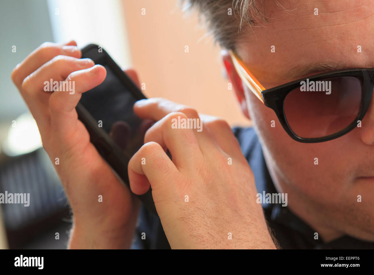 L'homme avec la cécité congénitale à l'aide de dispositifs facilitant l'écoute dans son téléphone cellulaire Banque D'Images