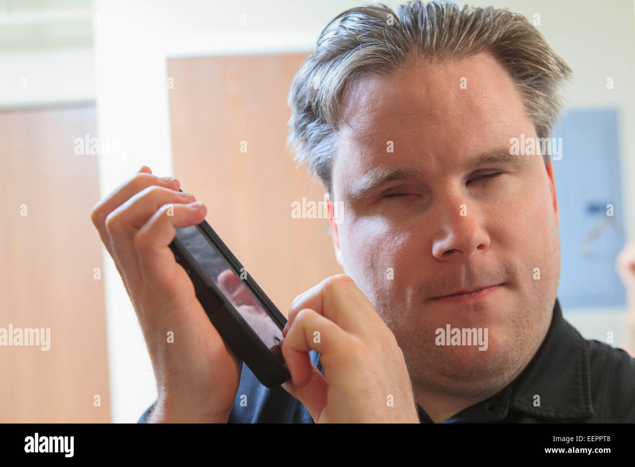 L'homme avec la cécité congénitale à l'aide de dispositifs facilitant l'écoute dans son téléphone cellulaire Banque D'Images